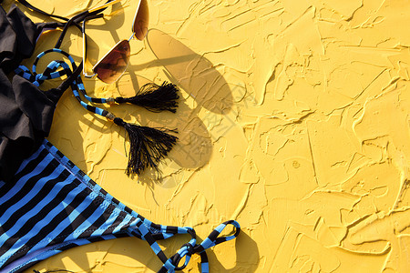 去痱防湿疹黄色背景上带黑色条纹的蓝色女性泳装和太阳镜 海滩度假的概念是去海边游泳的配件防紫外线晒黑 复制空间 弗拉特拉 配饰 假期背景