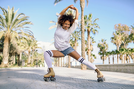 黑女人在溜冰鞋上 在沙滩中用棕榈树编舞 旱冰鞋图片
