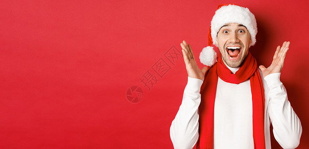 圣诞节 寒假和庆祝活动的概念 帅哥对新年促销优惠感到惊讶 微笑着惊讶 站在红色背景上 购物 快乐背景图片