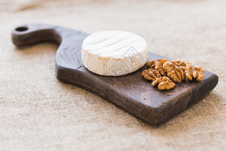 山羊乳酪奶油奶酪 咖啡干酪 新鲜的乳酪 在木板上配有坚果和葡萄 意大利菜和法式奶酪 节食 小屋背景