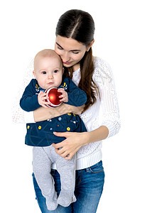 抱着球孩子一个幸福的母亲抱着一个小女儿 带着一棵圣诞树 冬天 家背景