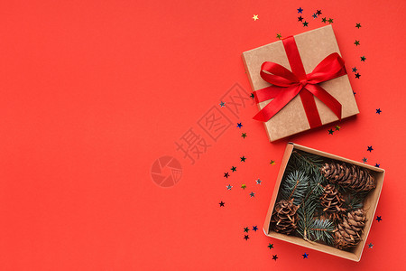 红色雪松丝带红色上打开的礼品盒中的天然锥体背景