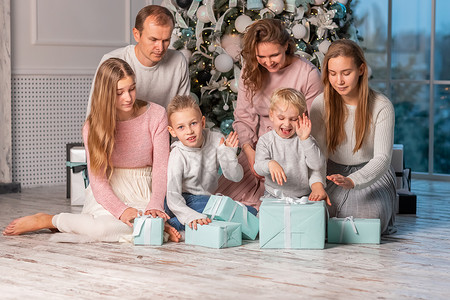 很多的礼物快乐的大家庭 有很多孩子在圣诞前夕在圣诞树下打开礼物 圣诞老人 童年背景