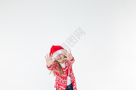 带帽子情快乐的女孩跳舞的画像 穿着红色圣诞毛衣和孤立在白色背景上的圣诞老人帽子 穿着圣诞马鹿毛衣的年轻白种人快乐微笑的金发女孩很开心 情背景
