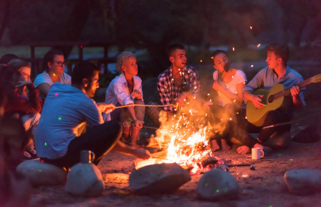 年轻朋友在营火周围放松 喝 户外 野餐 篝火 家庭高清图片