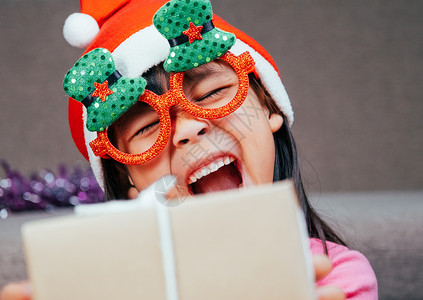 快乐的小女孩在圣诞老人的帽子在家里送圣诞礼物 新年快乐 圣诞快乐 微笑 假期背景图片