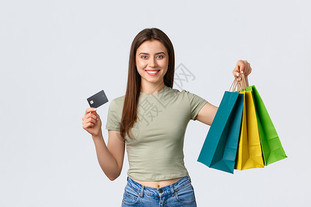 兴奋的女孩为暑假买新衣服 微笑和展示信用卡 并配有袋包商店 白背景的彩礼卡; 在购物市场 生活方式和时装概念上背景图片