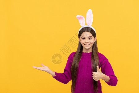 竖起双耳的兔子复活节快乐的少女戴着滑稽的兔子耳朵展示产品 复制空间 复活节快乐背景