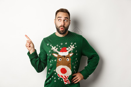 冬假和圣诞节 人们对新年购物宣传感到好奇 穿着滑稽的毛衣站在白色背景下站着 成人 快乐的背景图片