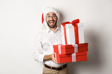 冬季假期和庆祝活动 快乐的人带来圣诞礼物 拿着礼物 戴着圣诞帽 站在白色背景上 促销 套装背景图片