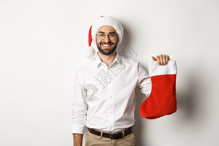 圣诞快乐 假期概念 快乐的成年男人得到礼物 在xmas袜子 看起来很兴奋 穿着圣塔帽 白色背景 冬天 时尚背景图片