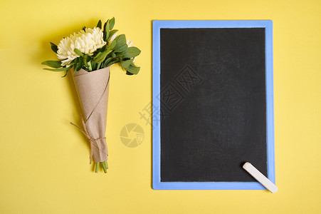 一束精致的秋季紫苑花的平铺组合物 用绳子绑在工艺包装纸上 空白的空黑板在黄色背景上有文字空间背景图片