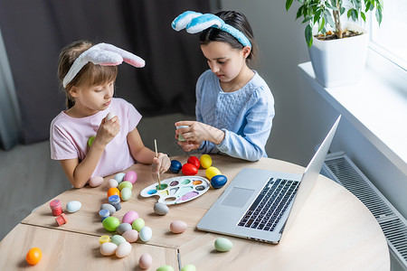 两个彩蛋两个长着兔耳朵的可爱小女孩正在画复活节彩蛋 孩子们正在为春假做准备 复活节的心情 孩子们正在画彩蛋 艺术疗法 桌子背景