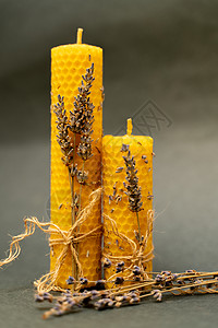 蜂窝蜡烛在灰色背景上 两根蜜蜂蜡烛 蜡烛装饰着熏衣草和黄麻绳背景