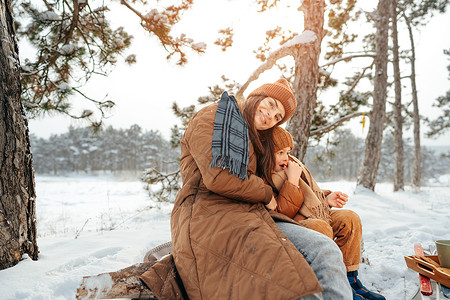 年轻女子和儿子在冬季森林野餐喝热茶 公园 寒冷的图片