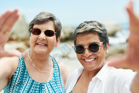 怎么能不在沙滩上自拍呢 拍摄的是两个成熟的朋友在海滩上度过一天时站在一起自拍背景图片