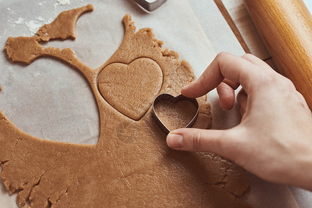 心形饼干制作情人节以心形做姜饼饼干 女性用手切曲棍球 假日食物概念 家 女士背景