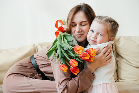 可爱的小女孩祝她母亲3月8日或母亲节生日快乐 送花 亲吻和拥抱背景图片
