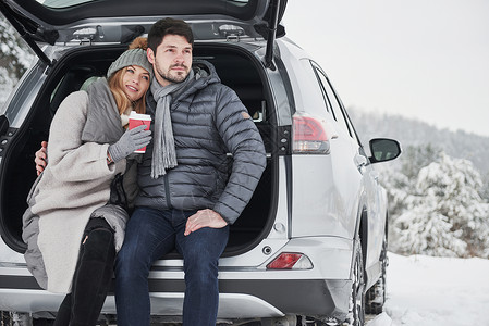 爱与家庭的概念 好情侣在冬天的乡村有周末 坐在现代汽车的后部 笑声  掌声 背景图片