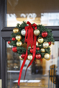 透明花环素材圣诞花圈 有装饰 棉花花朵挂在房子的透明门上; 在墙边布满了装饰品和鲜棉花 手工制作的背景