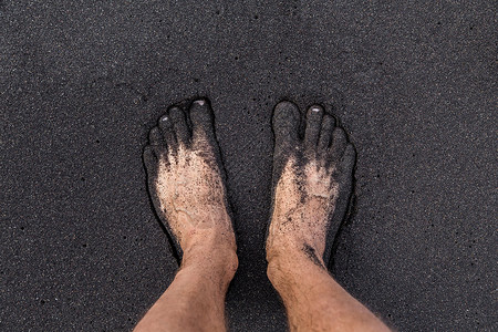 加那利人一个人赤脚站在特纳里费海滩的火山黑沙滩上 两英尺高在沙面上背景