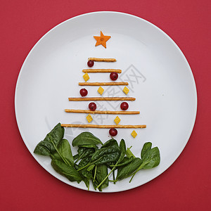 创意可食用的圣诞树 食物艺术最低限量主义 儿童食品和节日餐桌 红底盘上的木棍制成的树背景图片