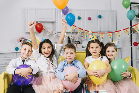 派对气球素材肖像坐在沙发上的孩子拿着气球背景