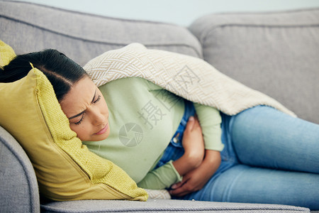 胃痛 经前综合症和坐在沙发上的女性 她们有压力 肠道健康不佳 胀气或肠易激综合征 腹部 消化不良或便秘图片