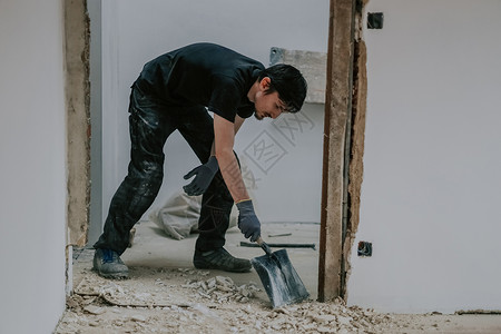 一名年轻男子用簸箕收集建筑垃圾图片