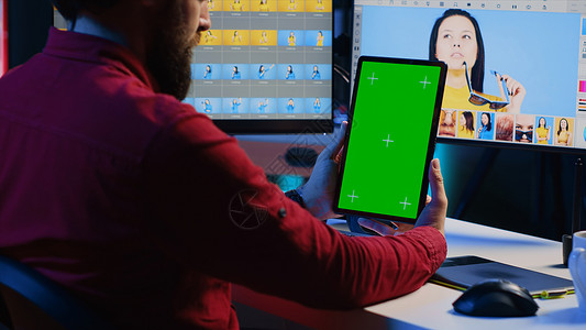 照片编辑人员在制作公司工作时通过绿屏平板电脑上的教程学习图片