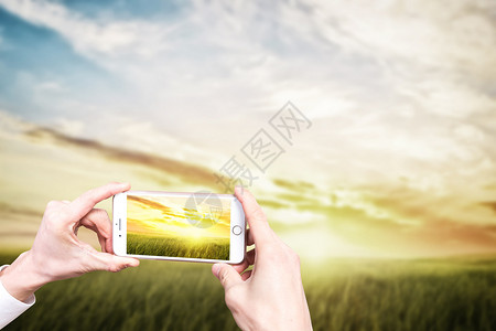 手机看日落手机摄影设计图片