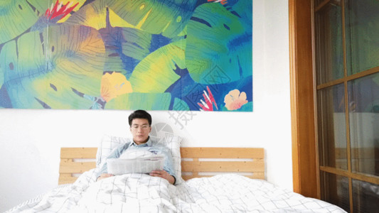 阅读杂志居家男性卧床休息GIF高清图片