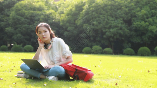 学习女性甜美大学生坐在草地上GIF高清图片