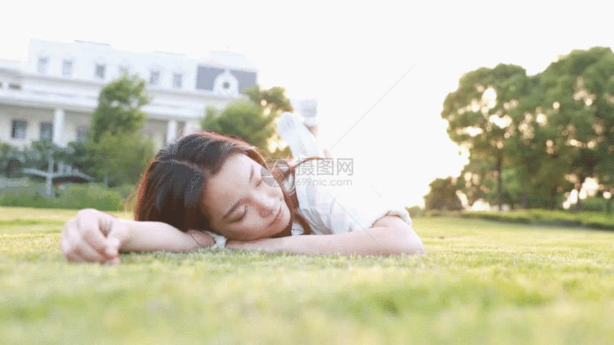 夕阳下大学生躺在草地上GIF图片