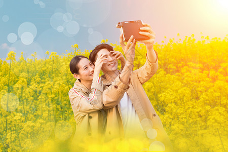 使用相机拍照的韩系女孩情侣在油菜花拍照设计图片