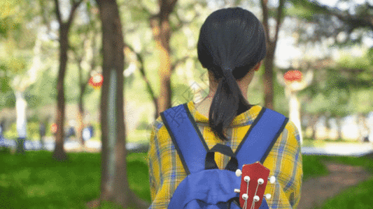 背着乐器在森林行走的女生背影GIF图片