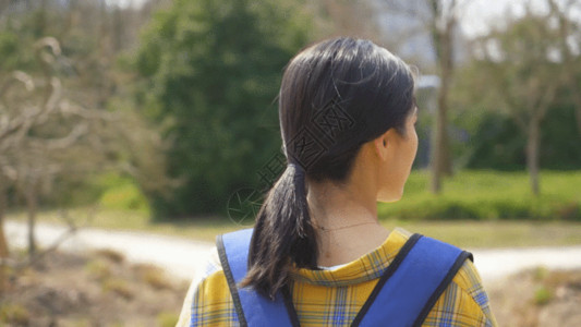 行走散步青年背着书包的女生户外郊游背影GIF高清图片