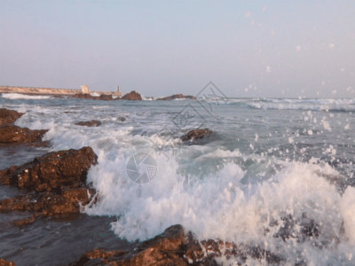 海岸上的灯塔大海浪花拍打礁石GIF高清图片