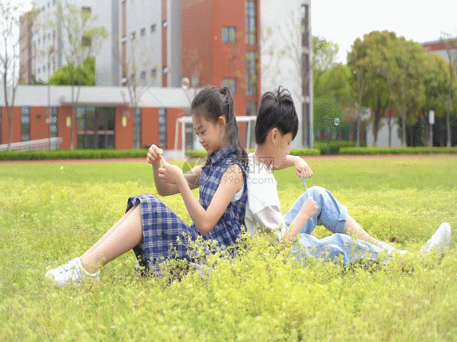 孩子们坐在草地上吹泡泡GIF图片