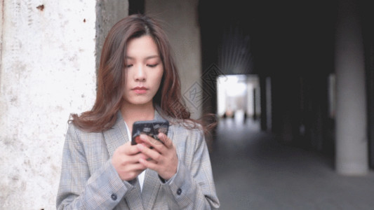 办公职场女性站在过道的职场女性使用手机GIF高清图片