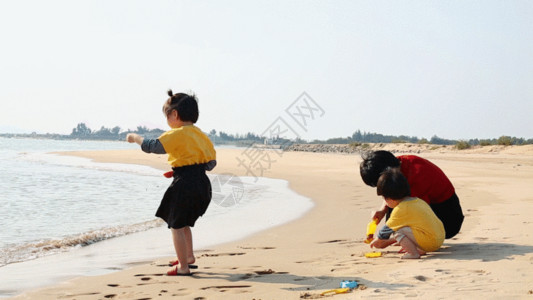 玩滑板的女孩妈妈带孩子在海边玩沙子GIF高清图片