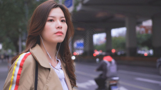 棕色全罩式耳机年轻女性在街边等车GIF高清图片