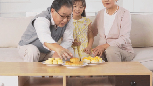 爷爷抱孙女中秋节爷爷奶奶和孙女在家吃月饼GIF高清图片