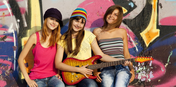 三个漂亮的女孩背景是吉他和涂鸦墙图片