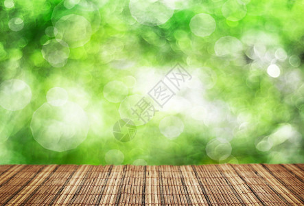 空竹桌和散焦的绿叶背景图片