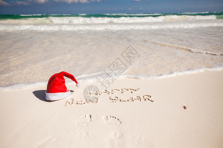 白沙滩上的圣诞帽子和新年快乐图片