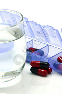 白底单独位剂量盒中的红和黑口服药胶囊背景图片