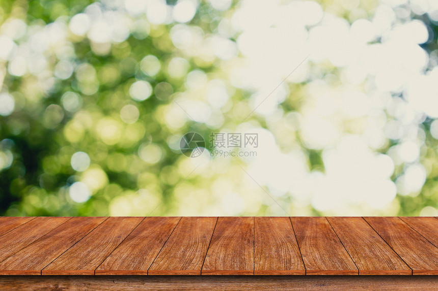 Bokeh抽象绿色背景上的木质表顶部可用于补装或图片