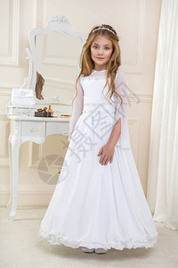 在婚纱店精心挑选婚纱的女孩穿着白圣餐礼服的美丽年轻女子模特站在一个设计图片