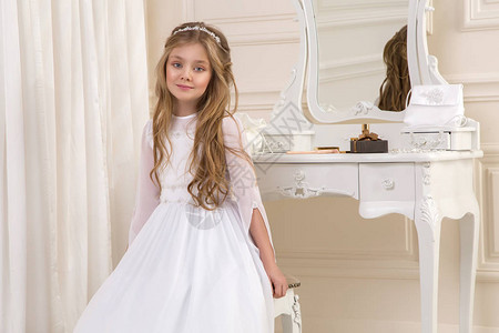 穿着白圣餐礼服的美丽年轻女子模特站在一个设计图片